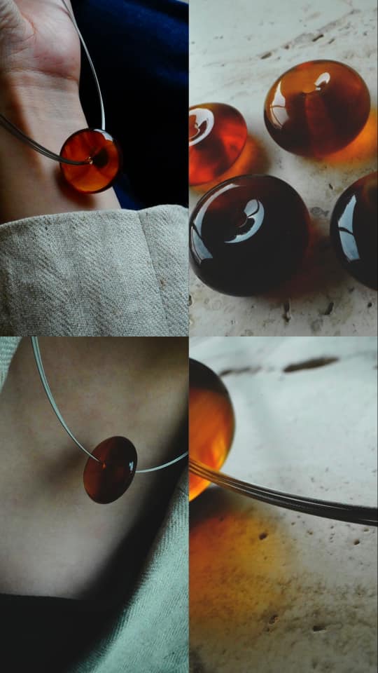 Burmese Amber Donut Necklace showcased on a hand alongside polished amber beads.