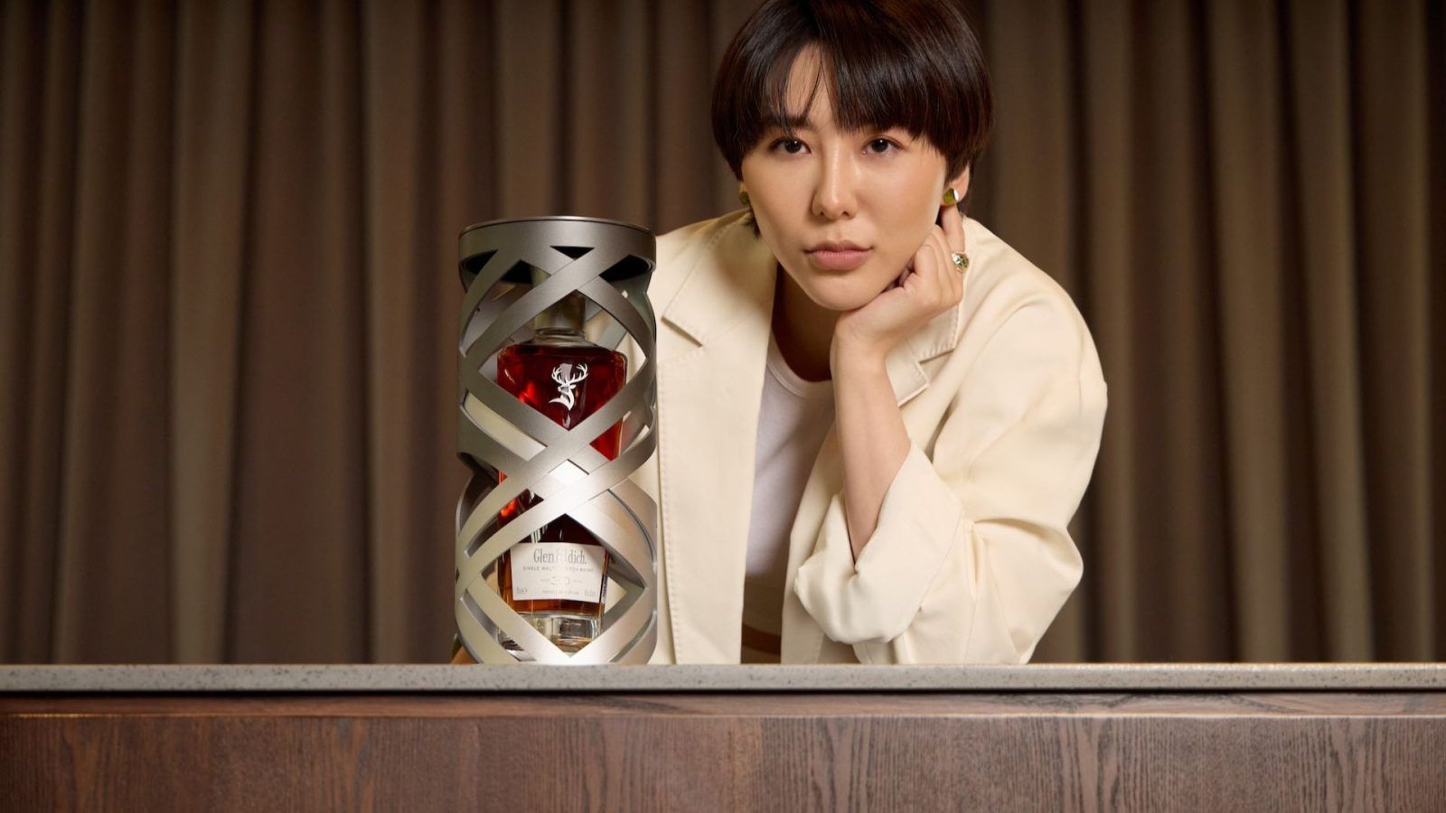 Michel Ong posing with a Glenfiddich bottle, emphasizing the connection between time and success.