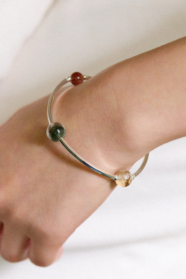 4Play Bangle featuring multicolored gemstones on a sterling silver wire worn on a wrist.