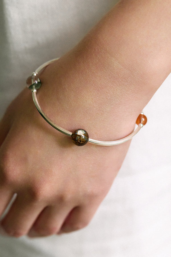 Close-up of a hand wearing the 4Play Bangle, featuring luminous gemstones and sterling silver design.