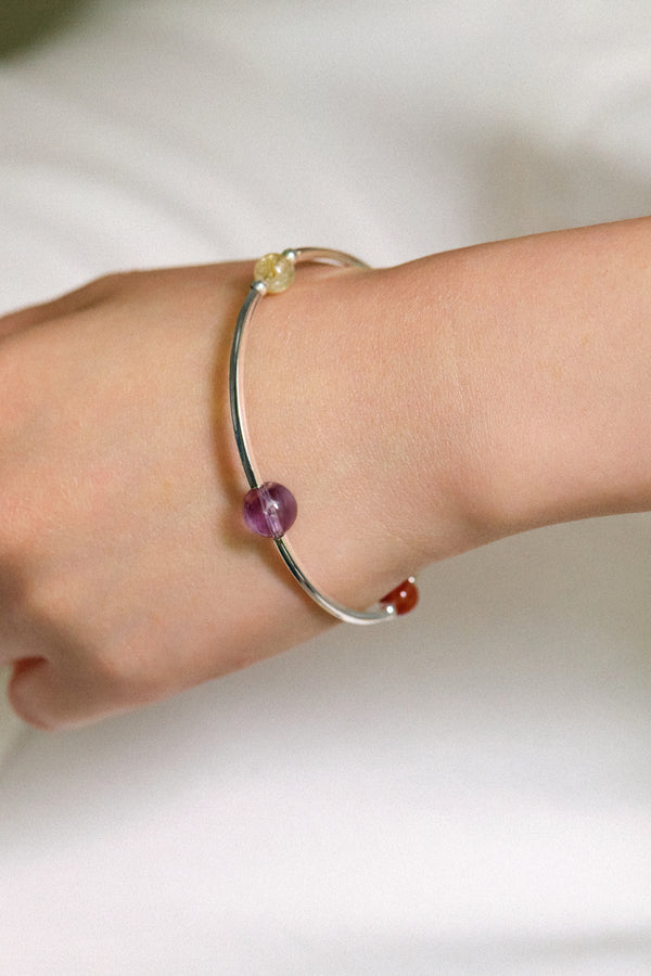 Close-up of a hand wearing the 4Play Bangle featuring colorful gemstones and silver design.