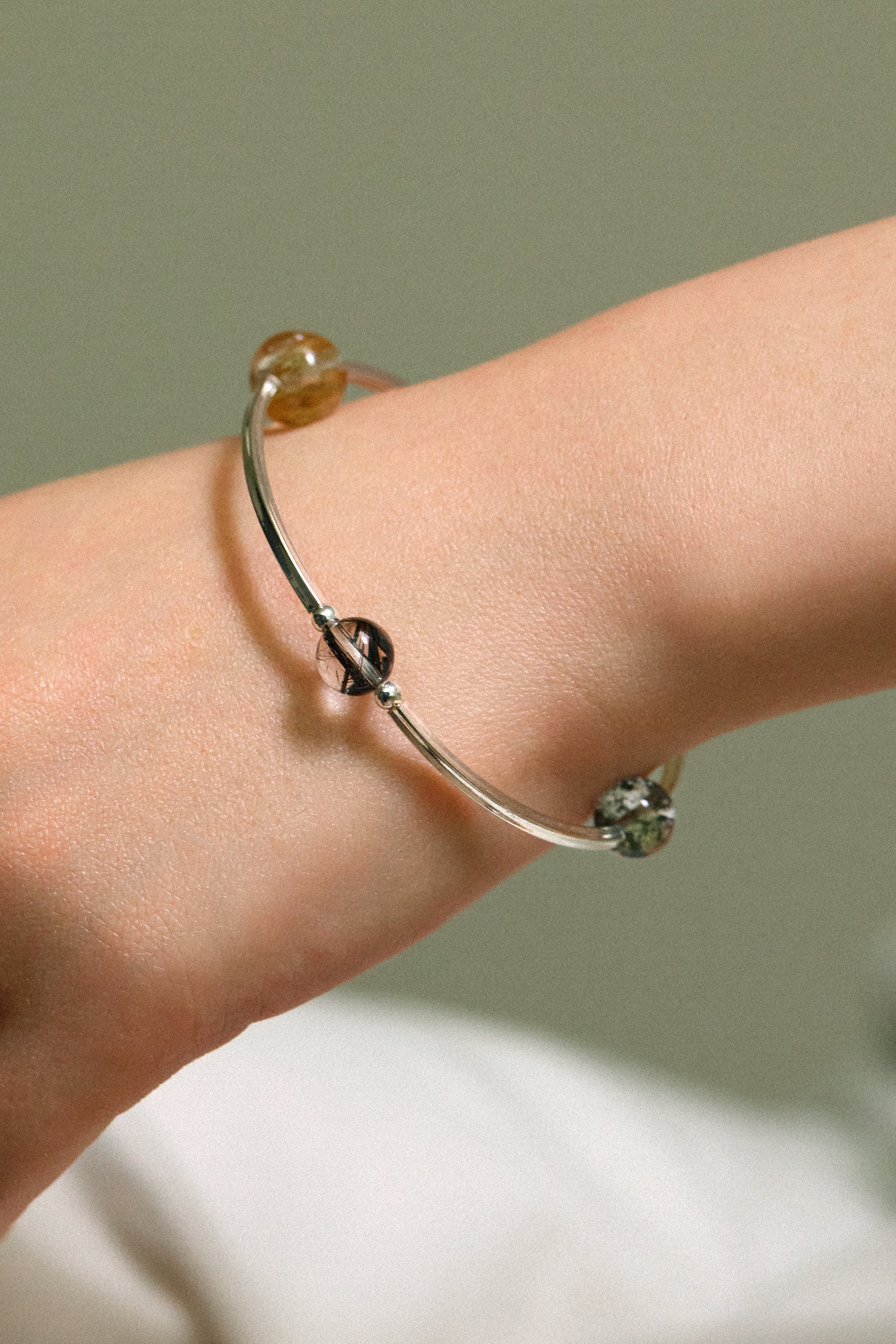 4Play Bangle featuring luminous gemstones on a slender sterling silver bracelet worn on a wrist.
