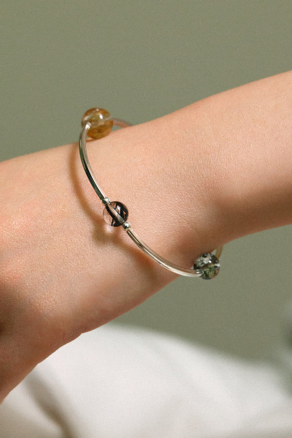 4Play Bangle featuring luminous gemstones on a slender sterling silver bracelet worn on a wrist.