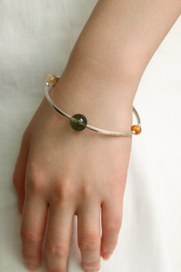 4Play Bangle featuring luminous gemstones encircled by sterling silver worn on a hand.
