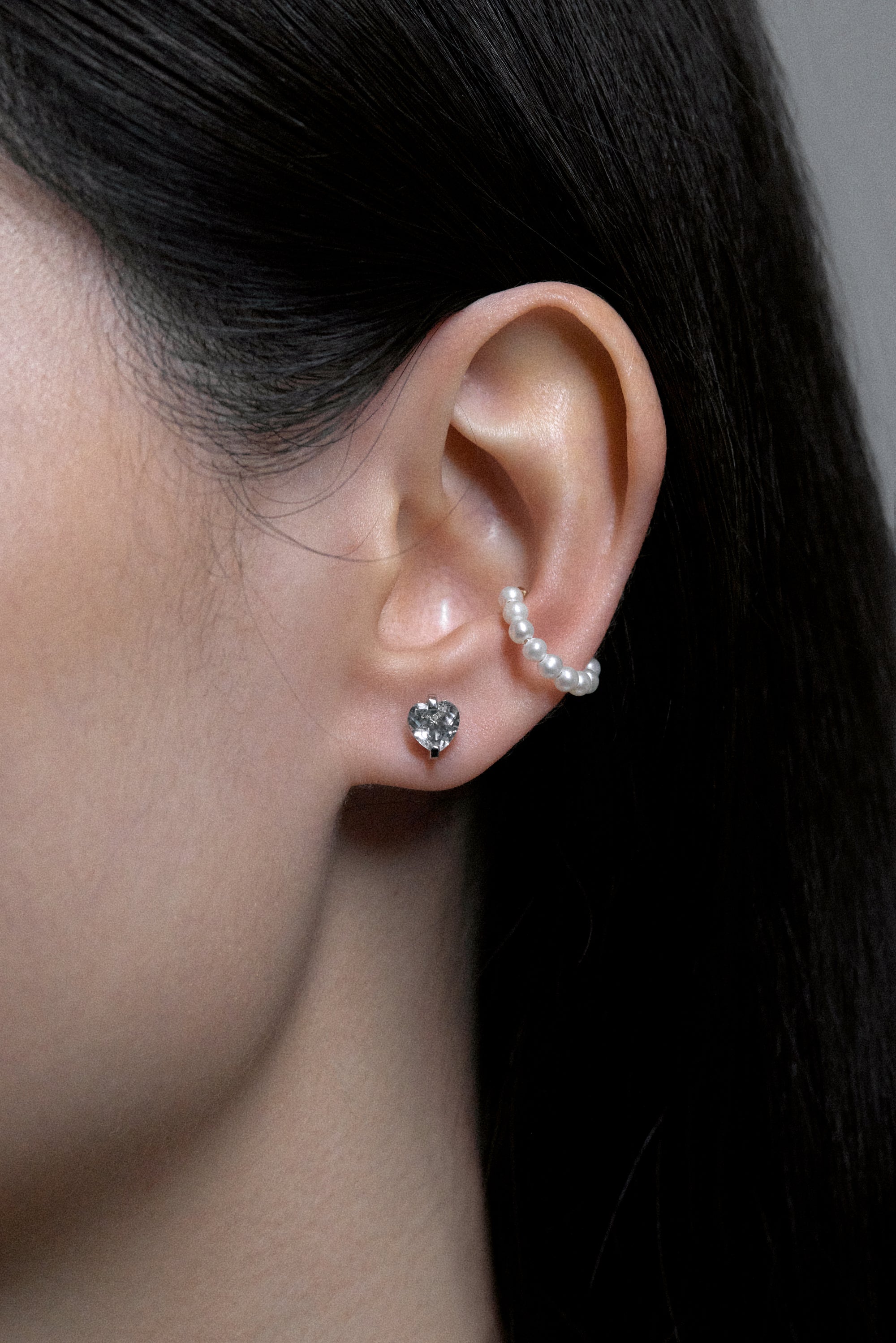 Close-up of a model wearing White Noise Pulse Studs crafted in sterling silver with water-clear rock crystals.