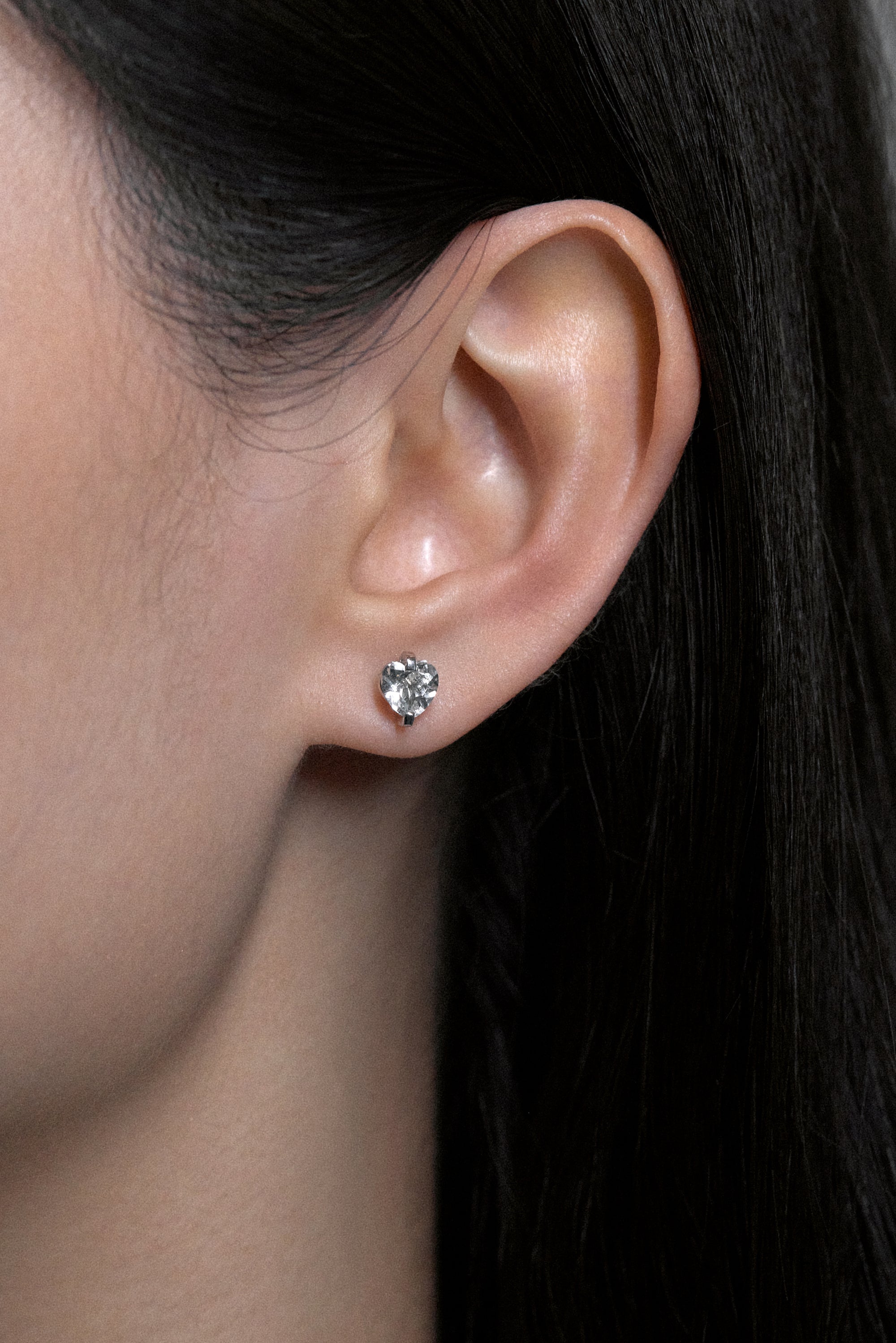 Close-up of ear featuring white noise pulse studs with hand-cut rock crystals in sterling silver.