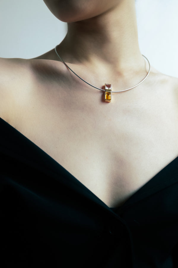 Elevé Yellow Emerald and Topaz pipe pendant worn on a stainless steel chain, showcasing sunny elegance and symmetry.
