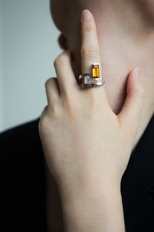 Close-up of a hand wearing an Elevé staircase ring featuring step-cut Yellow Emerald and Topaz in 18k Gold.