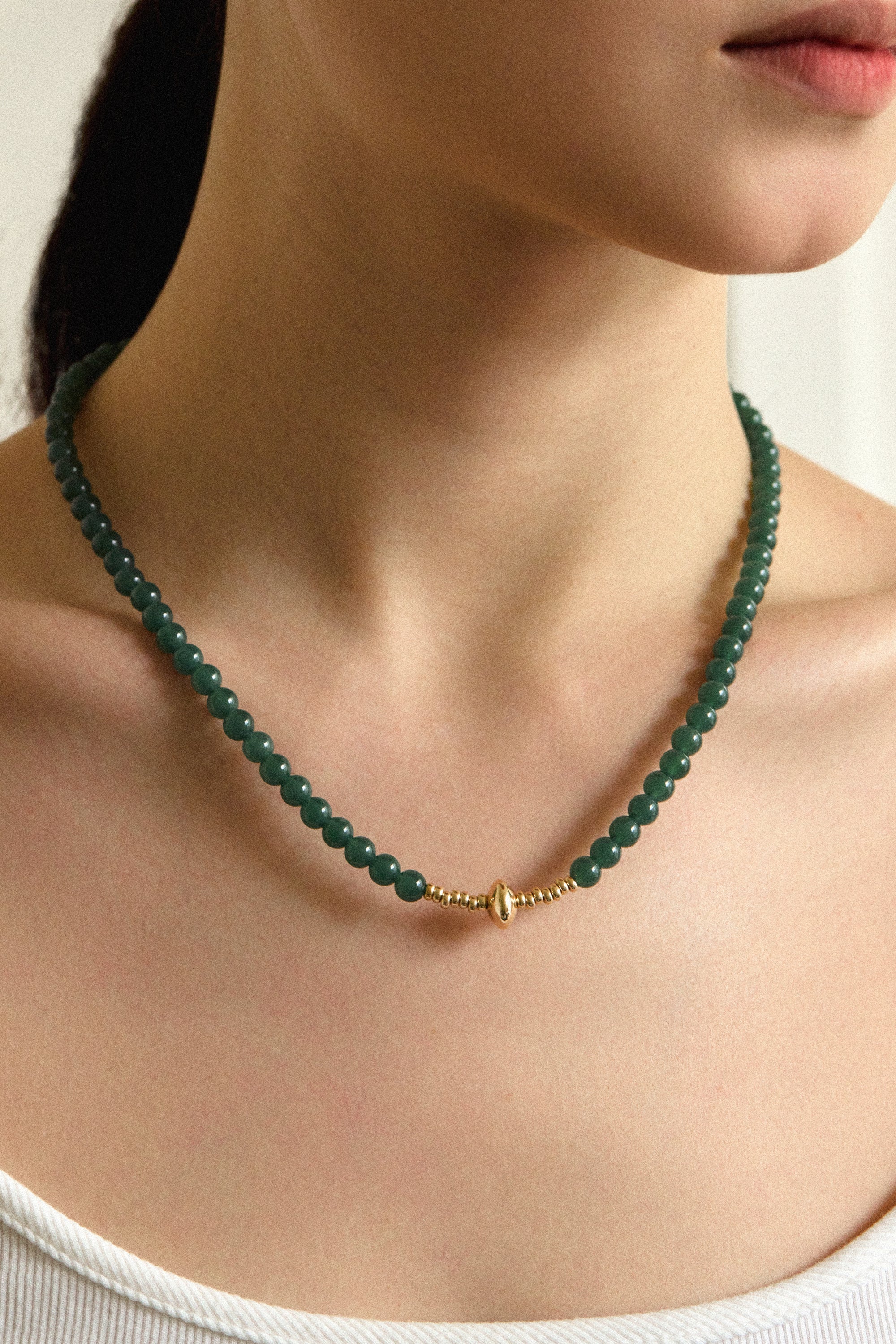 Green Alloy Jadeite Necklace showcasing rounded jadeite beads and a sculpted gold centerpiece worn by a model.
