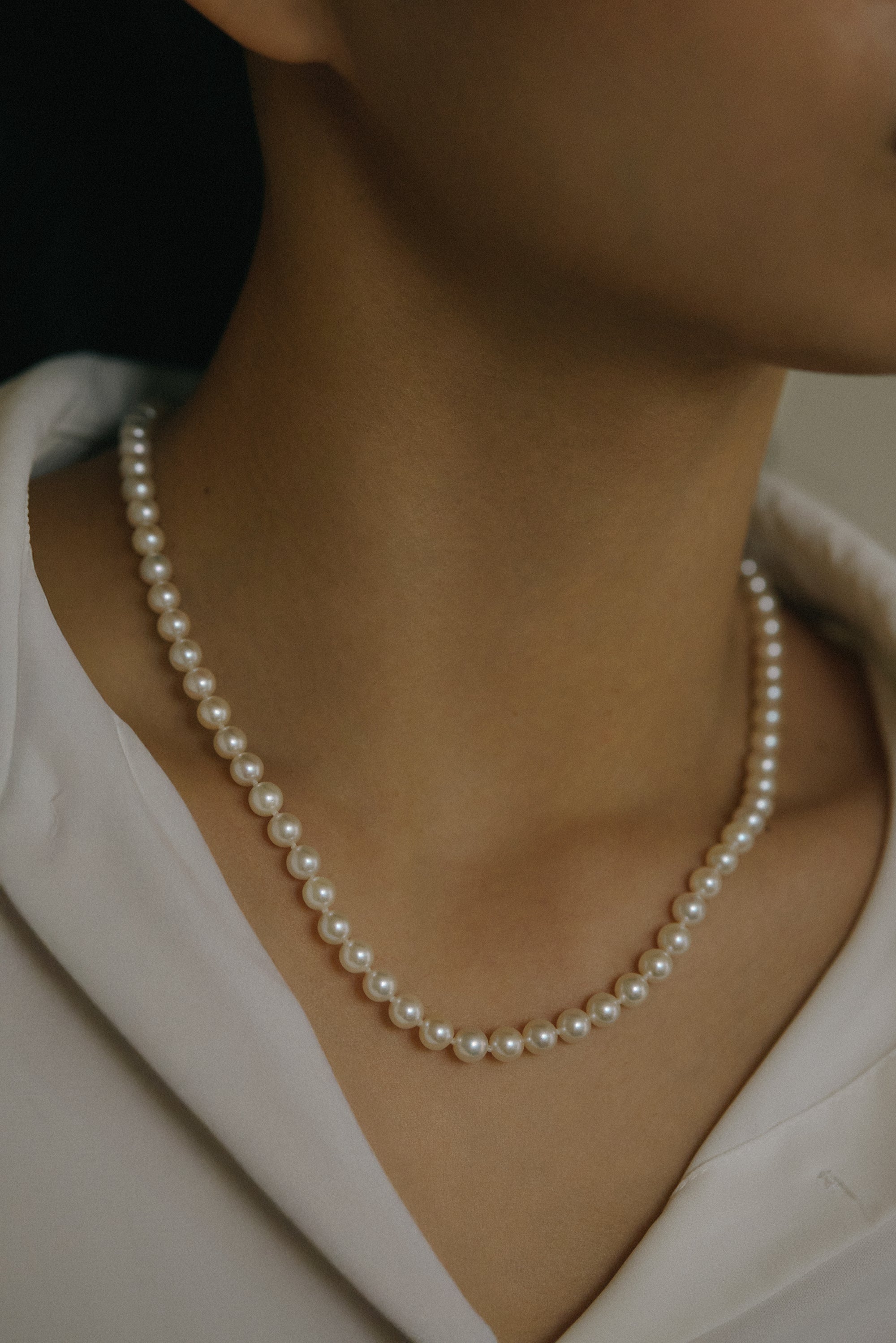 Elegant Akoya pearl necklace featuring perfectly round pearls on a stylish model, showcasing timeless sophistication.