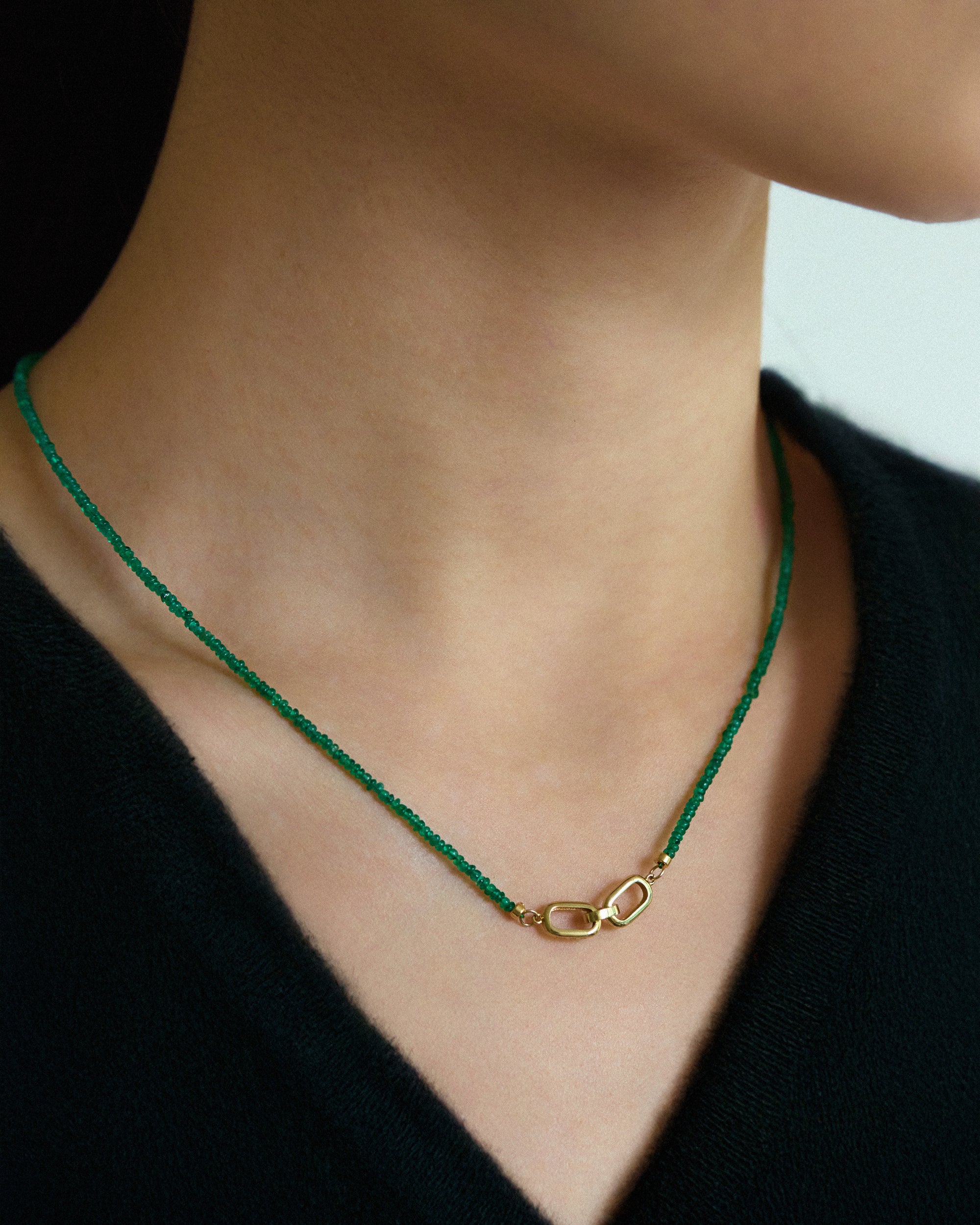 Muzo Emerald Necklace featuring Colombian emerald beads and a gold clasp, elegantly displayed on a model's neck.