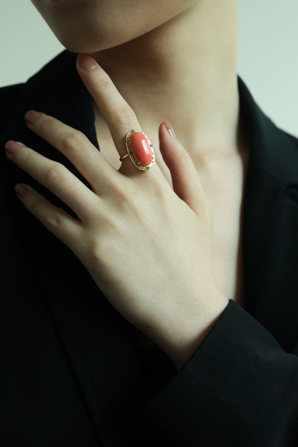 Close-up of a hand wearing a Momo Coral Tsavorite ring in 18k gold, showcasing vibrant colors.