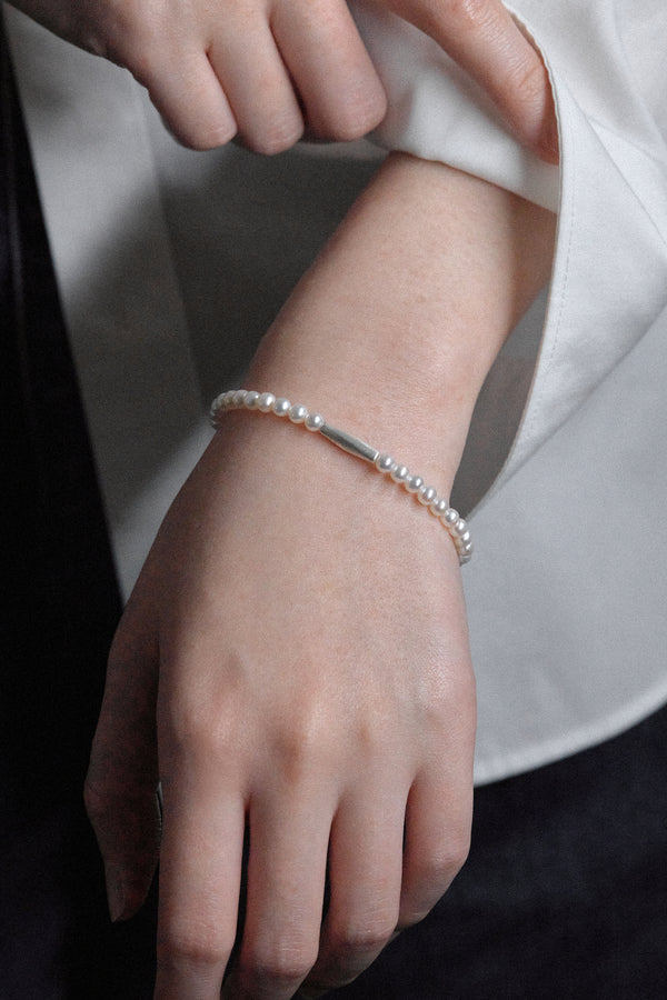 Baby freshwater pearl bracelet worn on a hand, featuring lustrous freshwater pearls and a matte silver clasp.