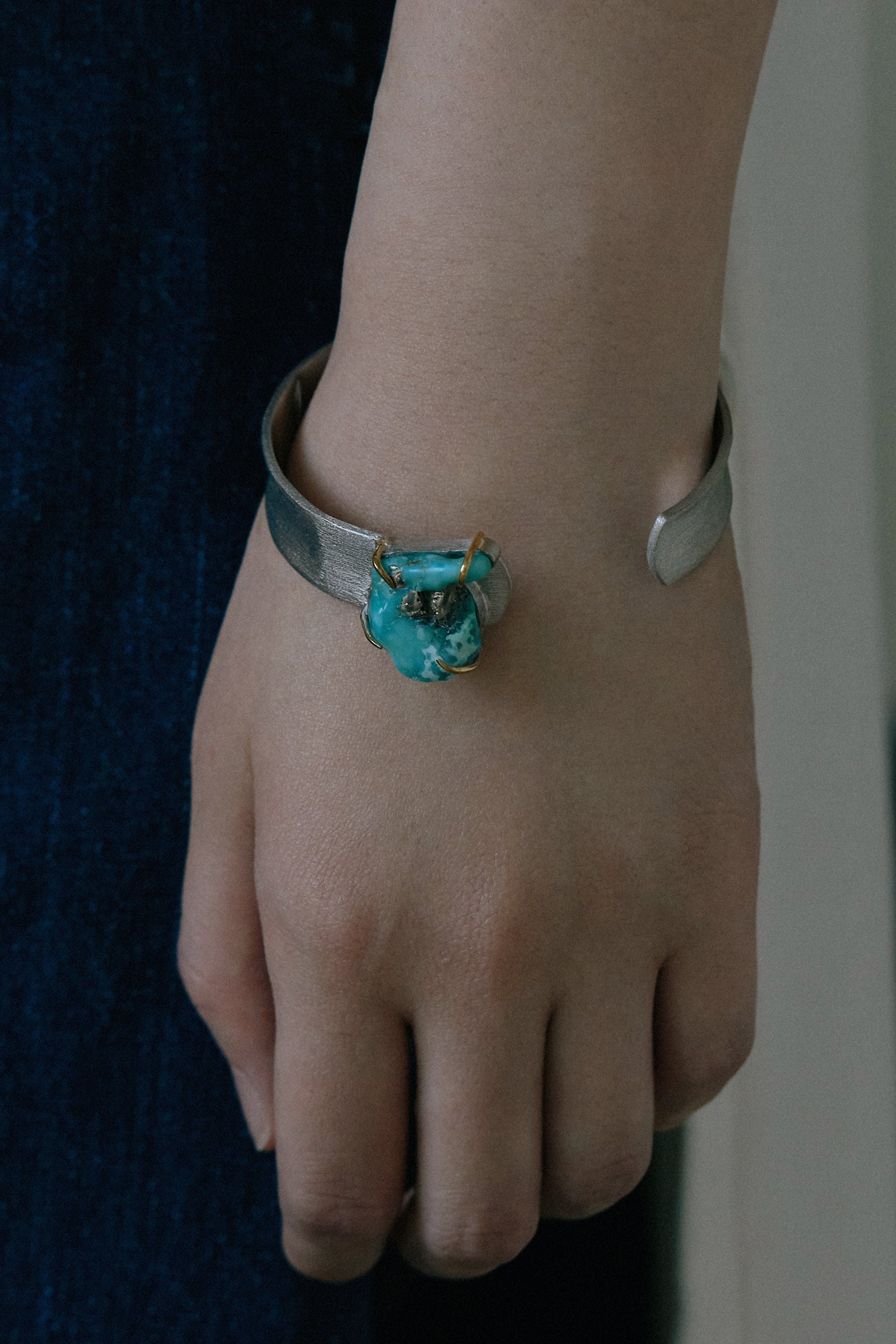 Handmade raw turquoise bangle on a hand, featuring a natural stone and silver band, showcasing unique organic design.