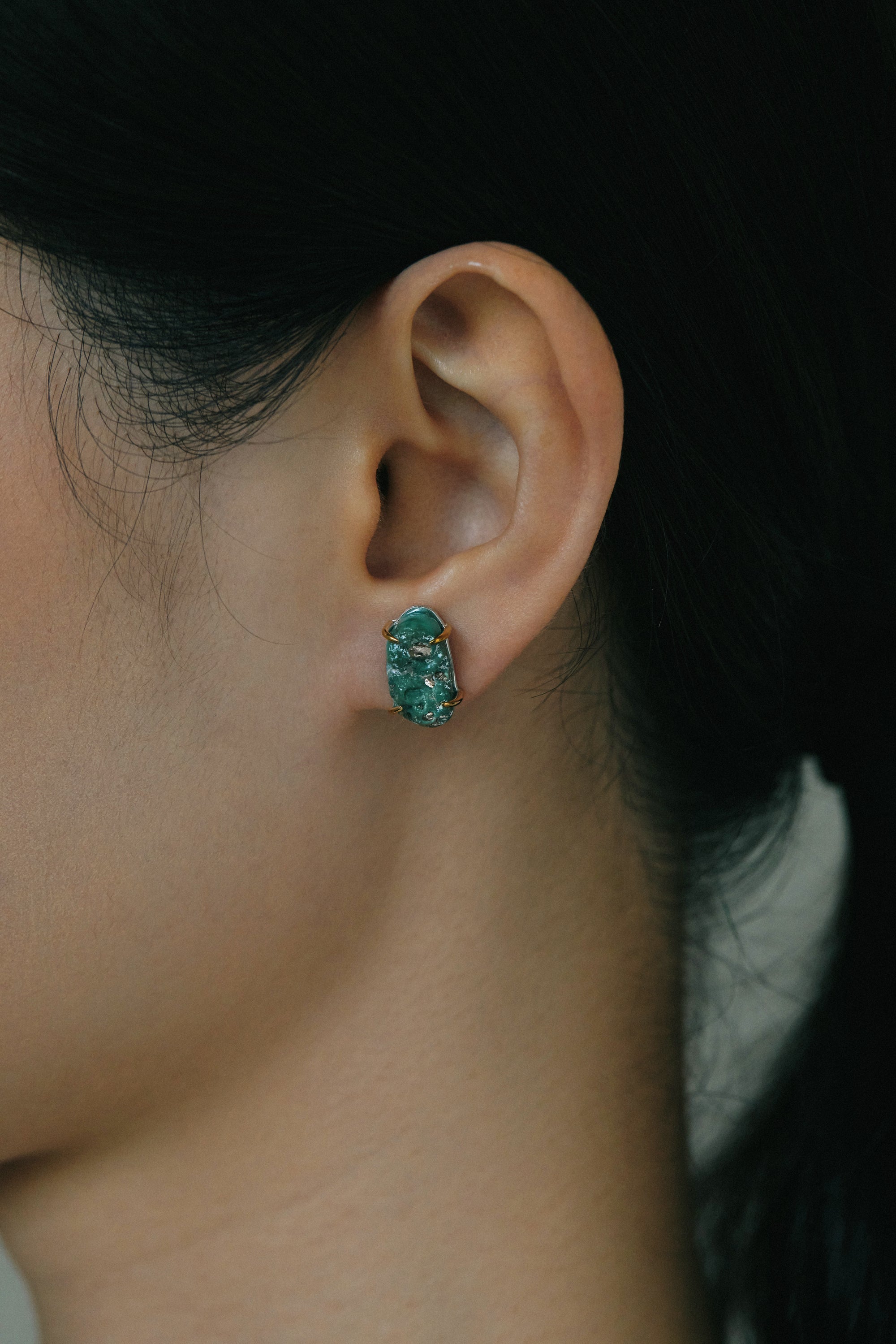 Close-up of a person's ear adorned with raw turquoise handmade ear studs, showcasing their unique beauty and earthy tones.