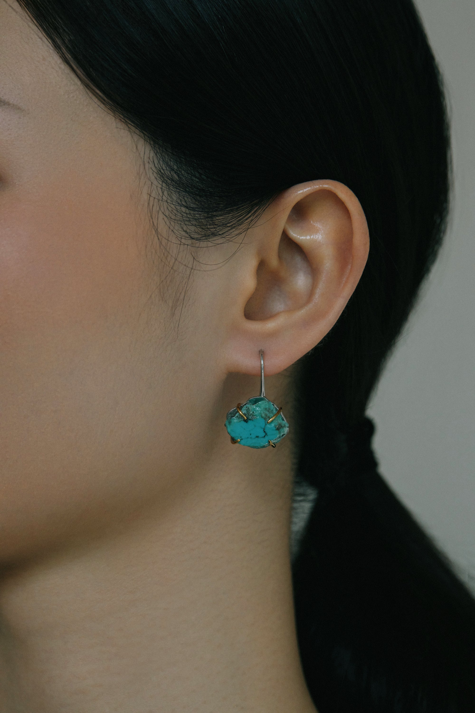 Raw turquoise handmade ear hook earrings showcased on model, highlighting their natural beauty and claw-set design.