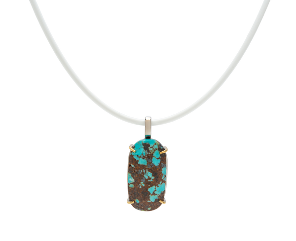 Handmade raw turquoise pendant with natural stone from Japan on a white cord, showcasing modern elegance and character.