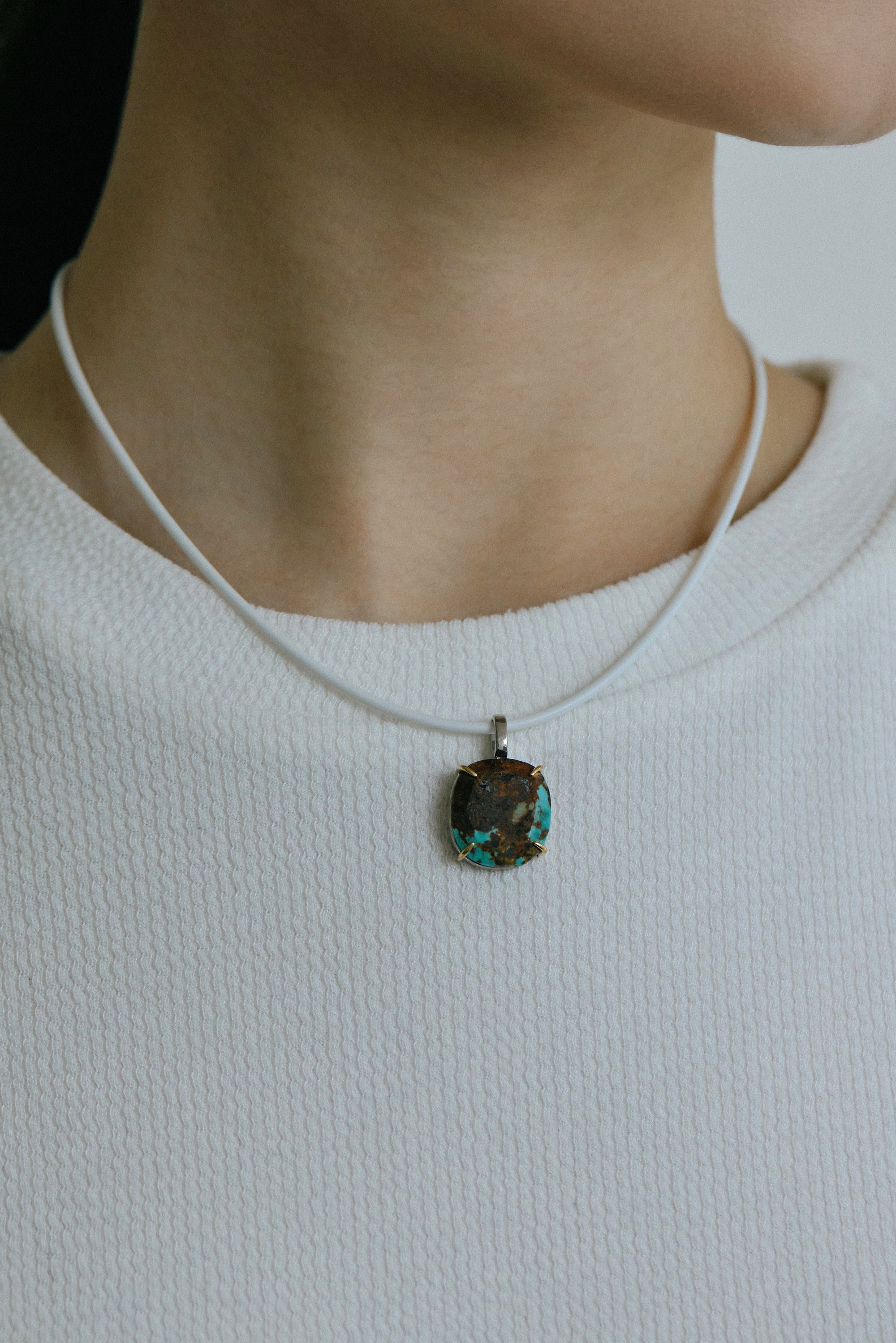 Turquoise handmade pendant necklace on a model, showcasing raw elegance and modern design.