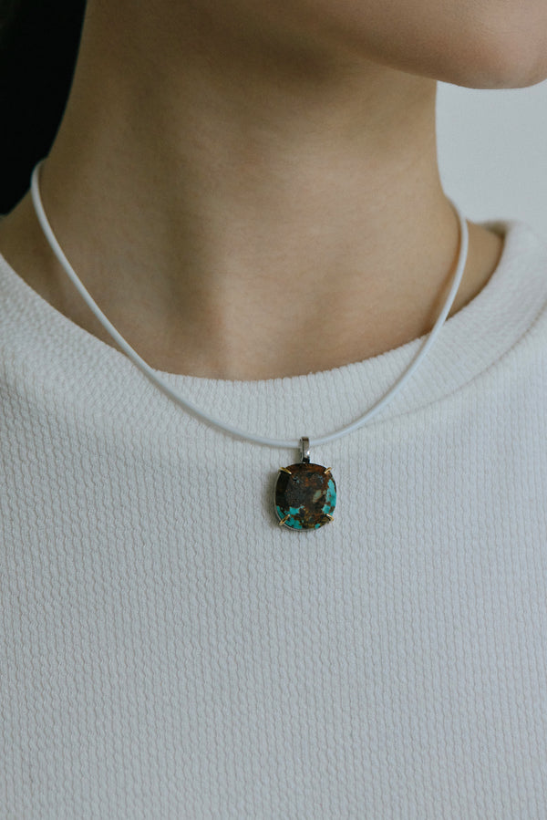 Turquoise handmade pendant necklace on a model, showcasing raw elegance and modern design.