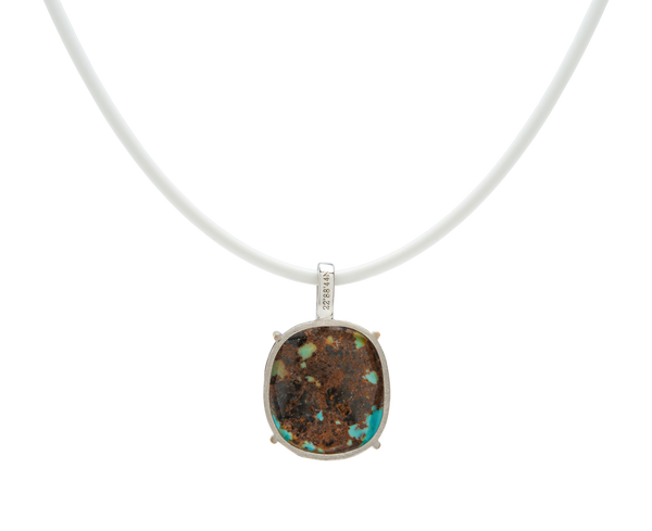 Turquoise handmade pendant necklace featuring a raw turquoise stone on a white cord.