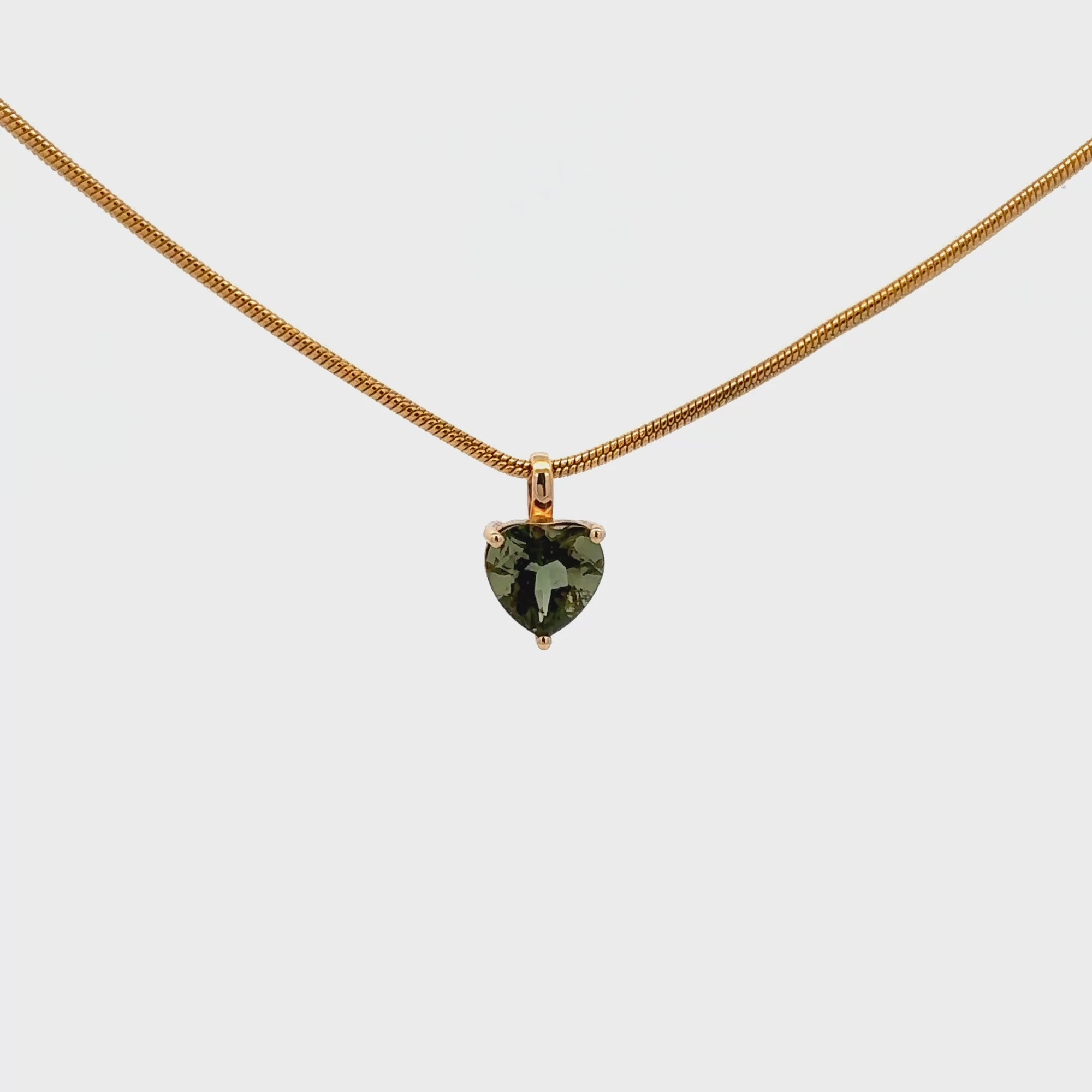 Moldavite heart pendant set in 18k gold, showcasing its olive-green hue and natural brilliance.